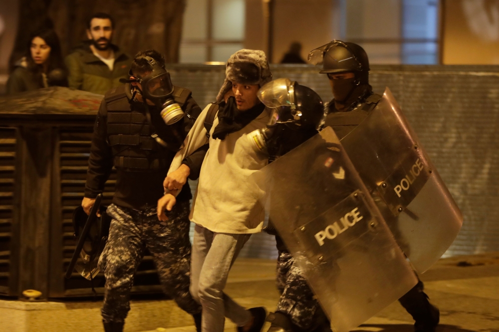 Riot police detain an anti-government demonstrator during clashes in the capital Beirut on December 14, 2019. AFP / Anwar Amro