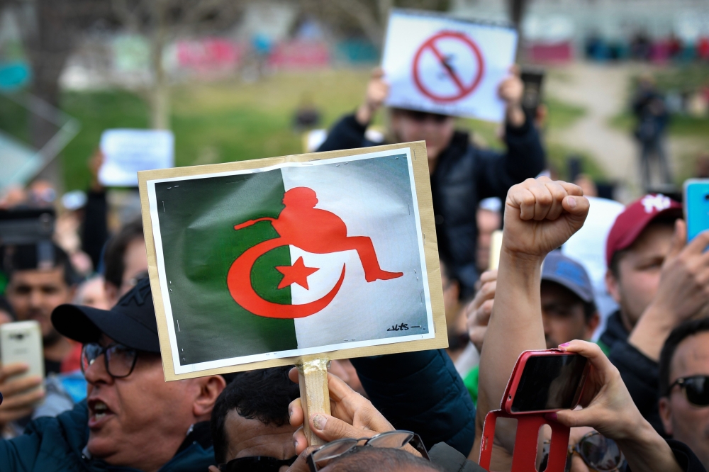 A file photo taken on March 03, 2019 shows protesters holding placards during a sit-in against the then Algerian president’s bid for a fifth term in office at the Porte d Aix in Marseille. AFP / Gerard Julien