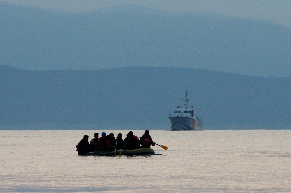 File photo: Migrants in a dinghy paddle their way on the Mediterranean Sea to attempt crossing to the Greek island of Kos as a Turkish Coast Guard ship patrols off the shores off Bodrum Sept 19, 2015. Reuters / Umit Bektas
