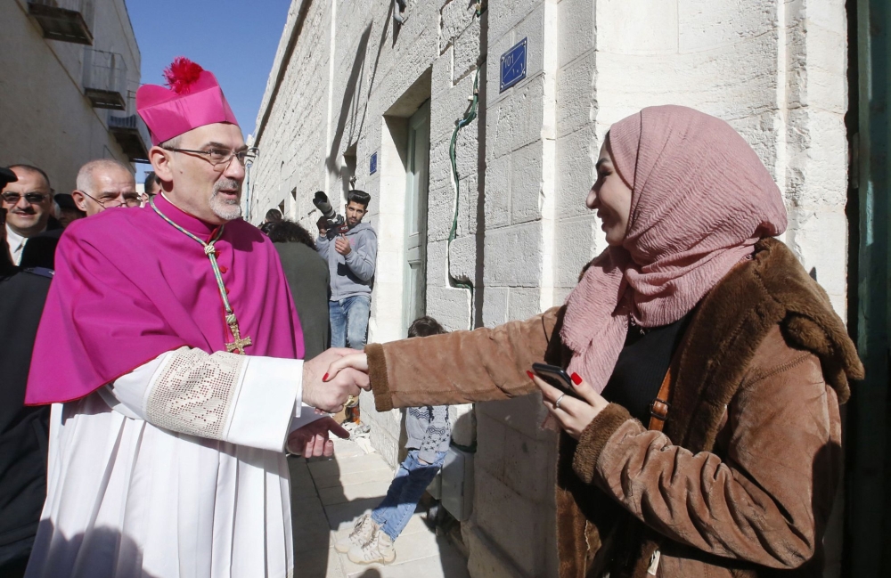 Apostolic Administrator of the Latin Patriarchate of Jerusalem Pierbattista Pizzaballa (L) is greeted by a Palestinian woman upon his arrival to the biblical West Bank city of Bethlehem on December 24, 2019. AFP / Hazem Bader 