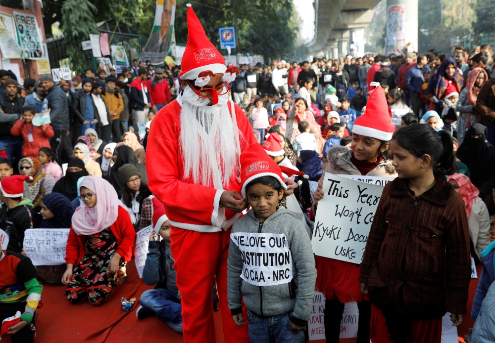 A man wearing a Santa Claus costume gives hats to kids during a protest against a new citizenship law, outside the Jamia Millia Islamia university in New Delhi, India, December 25, 2019. Reuters/Adnan Abidi