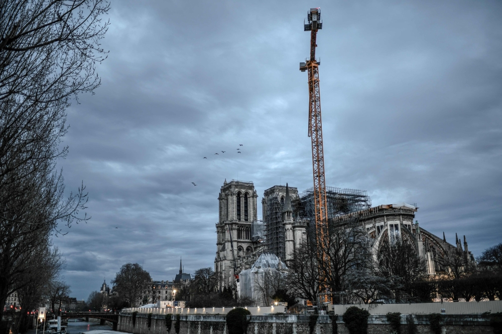 A picture taken on December 26, 2019 shows a giant crane outside the Notre-Dame Cathedral in Paris, which was partially destroyed when fire broke out beneath the roof on April 15, 2019.  AFP / Stephane De Sakutin