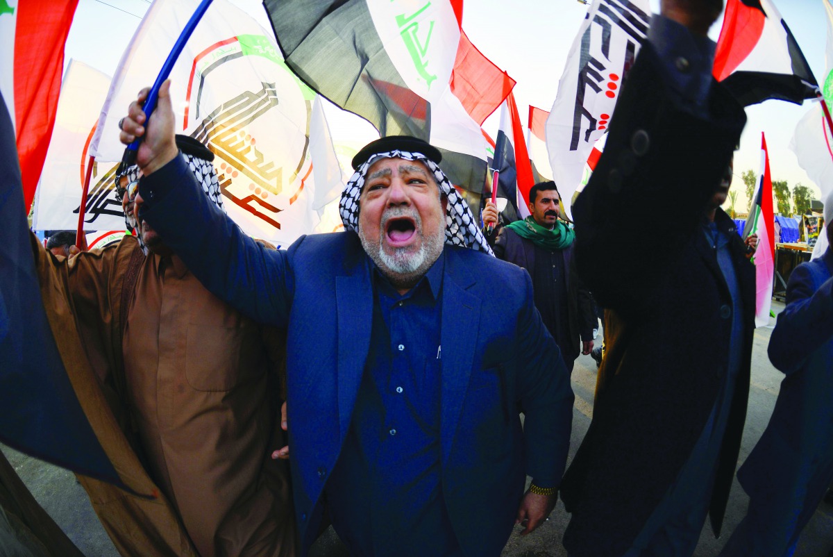 Iraqis wave Hashed Al-shaabi armed network flags on December 30, 2019, during a demonstration to denounce the previous night's attacks by US planes on several bases belonging to the Hezbollah brigades near Al-Qaim, an Iraqi district bordering Syria.  AFP 