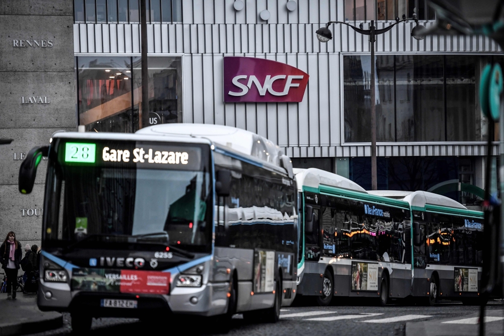 The logo of French national railway operator SNCF is seen as buses arrive outside Gare Montparnasse train station in Paris on January 2, 2020 on the 29th day of a nationwide multi-sector strike against the government's pensions overhaul. AFP / Stephane De