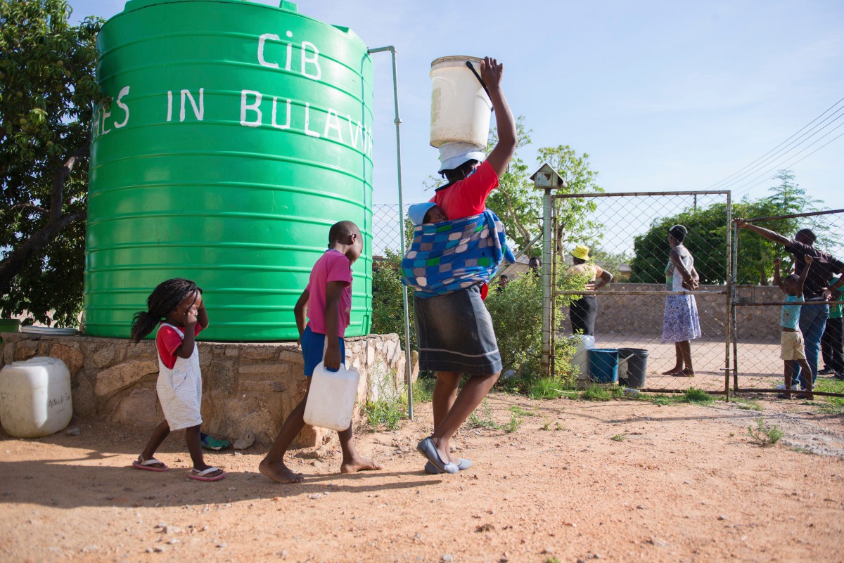 A woman and her children carrying water cans fetched from a tank installed at a church in Luveve on the outskirts of Bulawayo on November 24, 2016 AFP / Zinyange Auntony