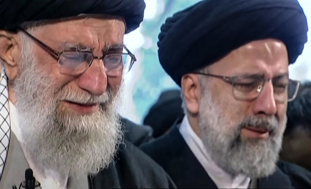 An image grab from an Iran Press video shows Iranian Supreme Leader Ayatollah Ali Khamenei (L) weeping as he recites a prayer in front of the coffin of slain Iranian military commander Qasem Soleimani duing a funeral procession in the capital Tehran on Ja