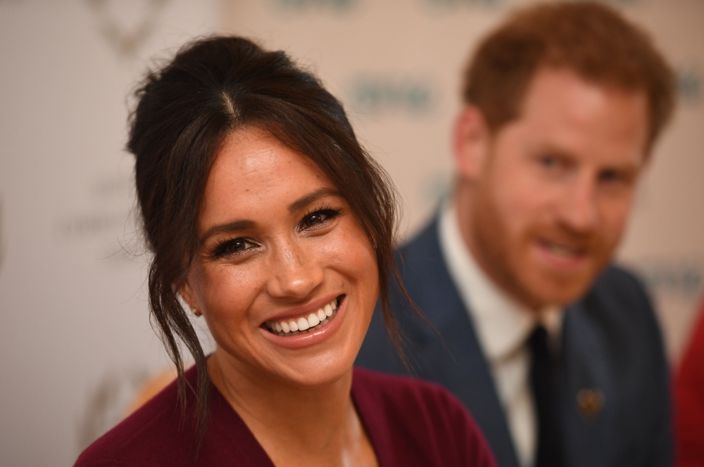 In this file photo taken on October 25, 2019 Britain's Prince Harry, Duke of Sussex (R) and Meghan, Duchess of Sussex attend a roundtable discussion on gender equality with The Queen’s Commonwealth Trust (QCT) and One Young World at Windsor Castle in Wind