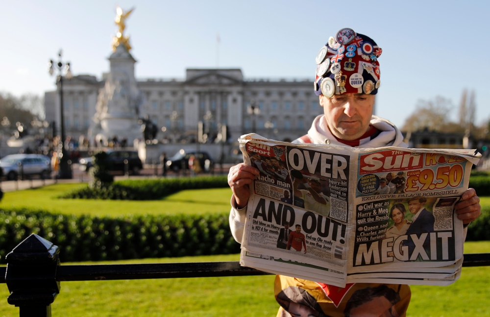 Royal super fan John Loughery holds a copy of a British newspaper as he poses for the media outside of Buckingham Palace in London on January 9, 2020. (AFP / Tolga AKMEN)
 