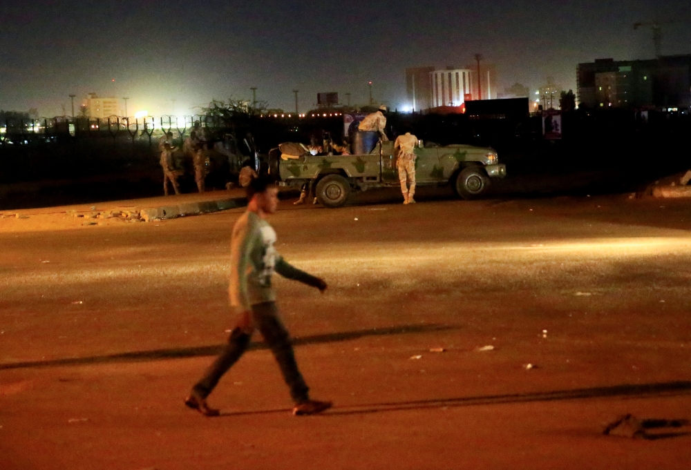 A civilian walks past members of the Sudanese Rapid Support Forces (RSF) are seen near the area where gunmen opened fire outside buildings used by Sudan's National Intelligence and Security Service (NISS) in Khartoum, Sudan January 14, 2020. REUTERS/Moham