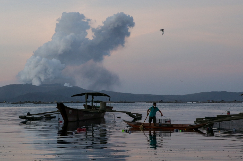 A fisherman catches fish as the Taal Volcano continuously errupts in Talisay, Batangas, Philippines, January 16, 2020. REUTERS/Eloisa Lopez