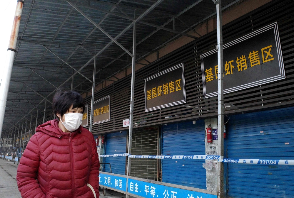 A woman walks in front of the closed Huanan wholesale seafood market, where health authorities say a man who died from a respiratory illness had purchased goods from, in the city of Wuhan, Hubei province, on January 12, 2020. AFP / Noel Celis
 