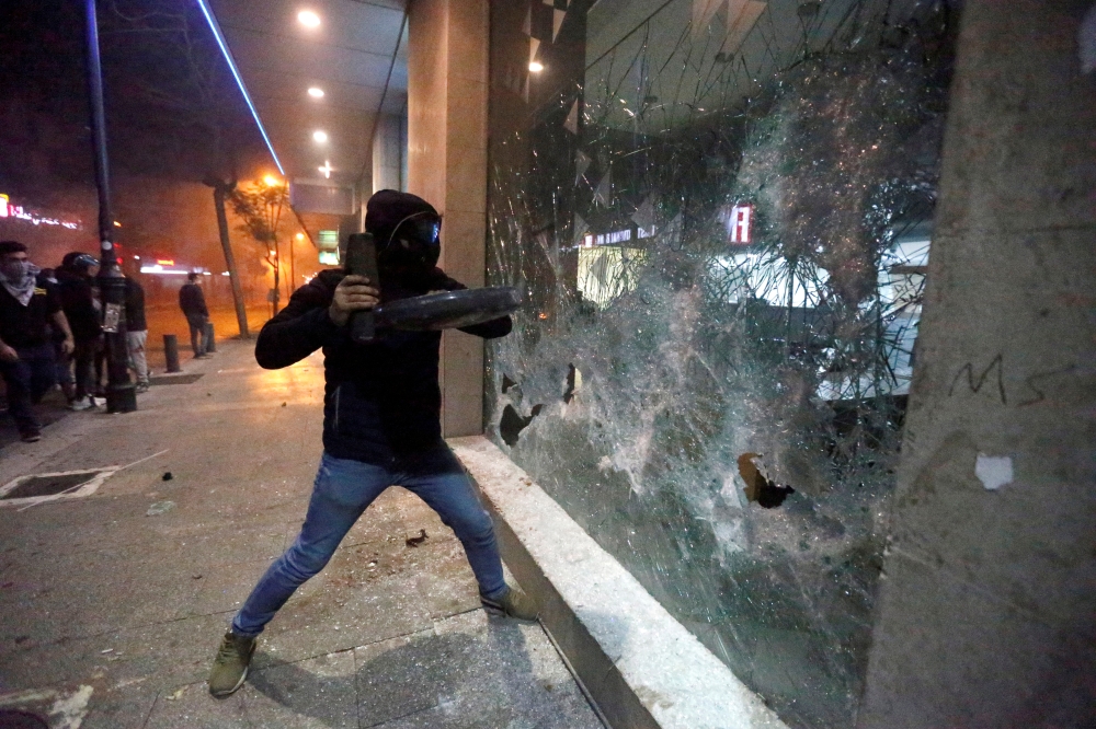 FILE PHOTO: Protesters smash the window of a bank as demonstrations against the government continue in Beirut, Lebanon January 14, 2020. REUTERS/Mohamed Azakir
