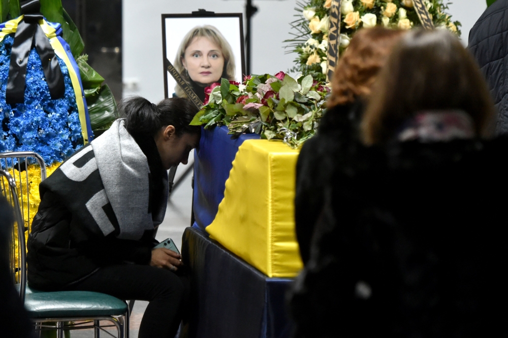 Relatives and colleagues attend a tribute ceremony and react in front of the flag-draped coffins of the 11 Ukrainians who died in a plane mistakenly shot down by Iran during a spike in tensions with Washington, which arrived in Boryapil airport, outside K