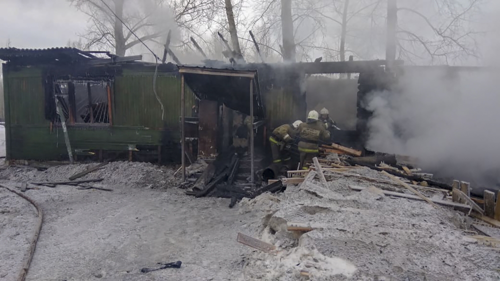This handout picture released by the Russian Emergencies Ministry shows firefighters working at the site of a fire that broke out in a one-storey wooden shack in the Prichulymsky settlement in Russia's Tomsk region on January 21, 2020. 