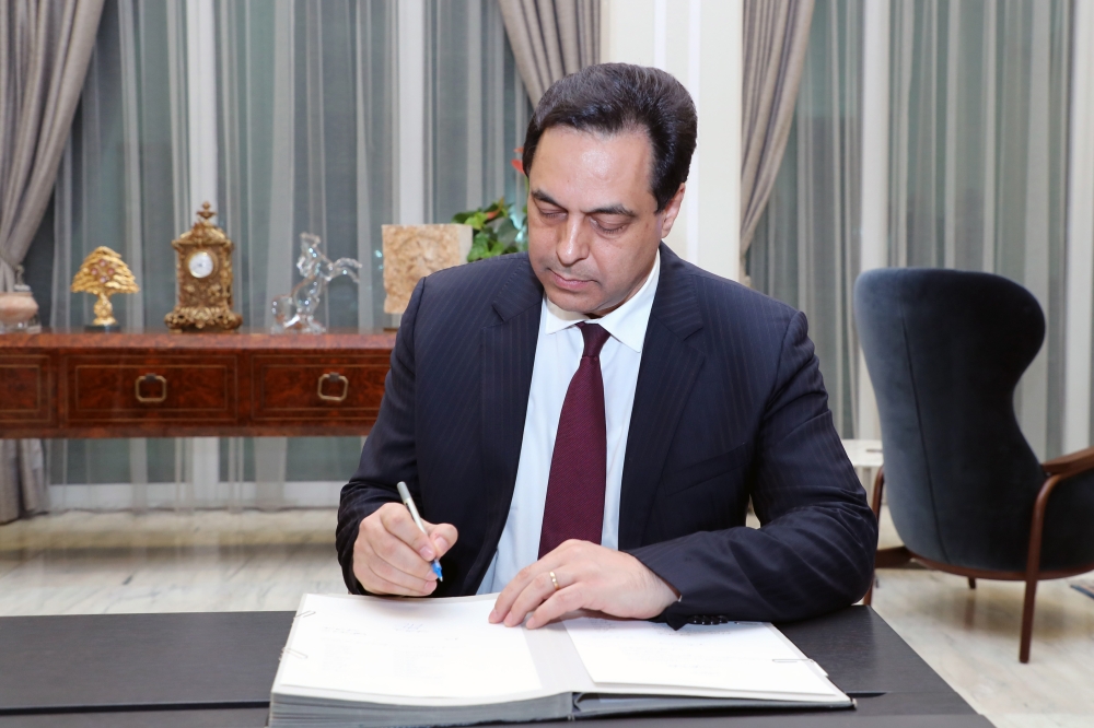 A handout picture provided by the Lebanese photo agency Dalati and Nohra on on January 21, 2020 shows Lebanon's new Prime Minister Hassan Diab signing official documents at the presidential palace in Baabda, east of the capital Beirut, as the new governme