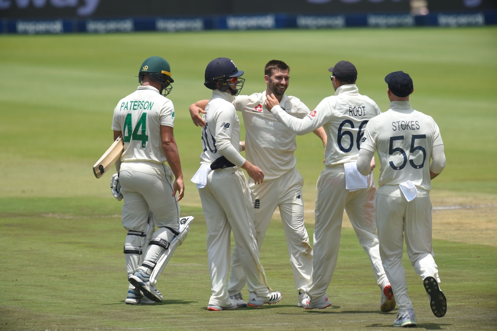 England's Mark Wood (C) celebrates with teammates after the dismissal of South Africa's Dane Paterson (L) during the third day of the fourth Test cricket match between South Africa and England at the Wanderers Stadium in Johannesburg on January 26, 2020. 