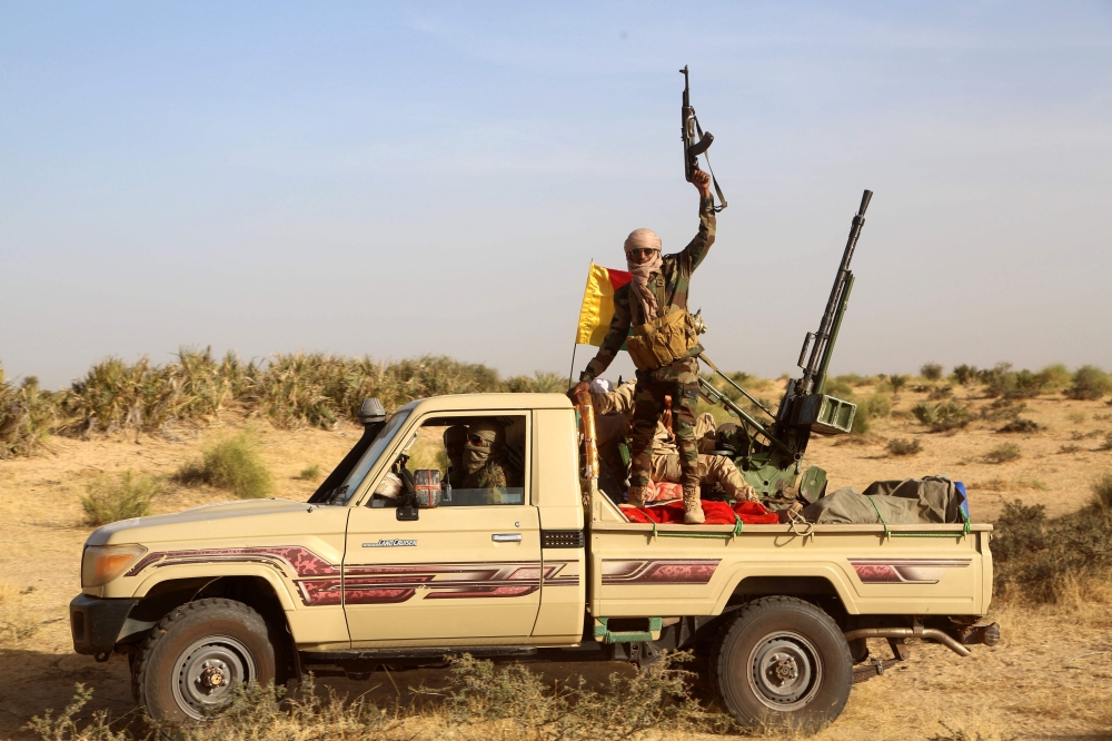 A Coalition of the People of Azawad (CPA) fighter raises his gun in the air while patrolling the area near the Mali-Mauritania border to protect local populations from insecurity related to unrest caused by bandits , in Soumpi on January 22, 2020. AFP / S