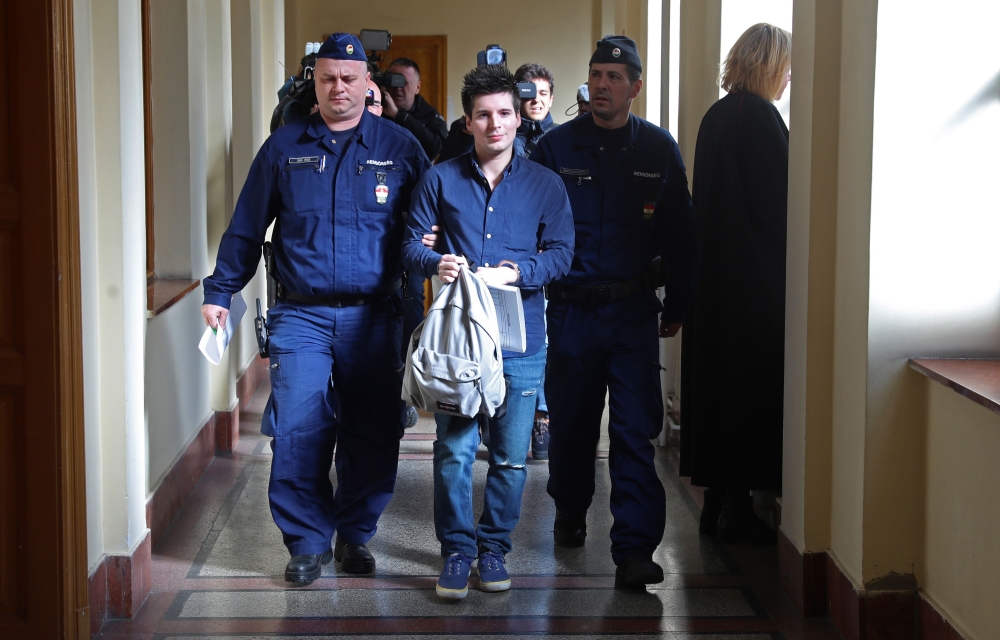 In this file photo taken on March 5, 2019 Football Leaks whistleblower Rui Pinto (C) is escorted by judicial officers as he arrives at the Metropolitan Court in Budapest, Hungary, for his trial. / AFP / FERENC ISZA