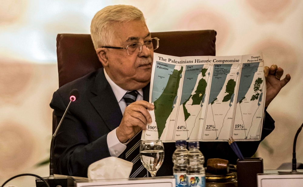 Palestinian president Mahmud Abbas holds a placard showing maps of (L to R) historical Palestine, the 1947 United Nations partition plan on Palestine, the 1948-1967 borders between the Palestinian territories and Israel, and a current map of the Palestini