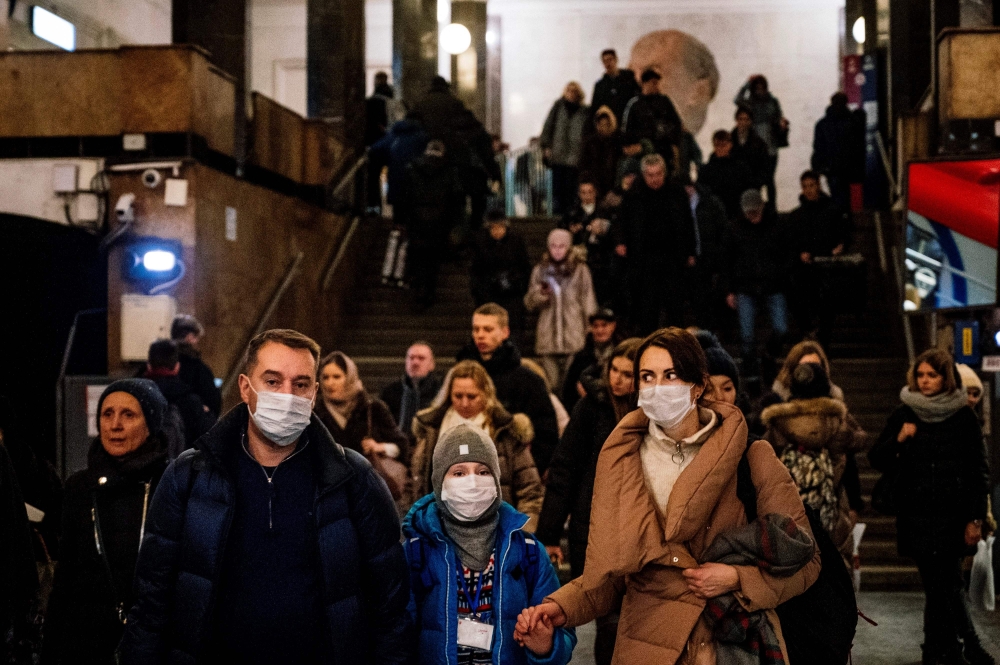 A family wearing a face mask walk in Biblioteka Imeni Lenina metro station in Moscow on February 7, 2020. / AFP / Dimitar DILKOFF 