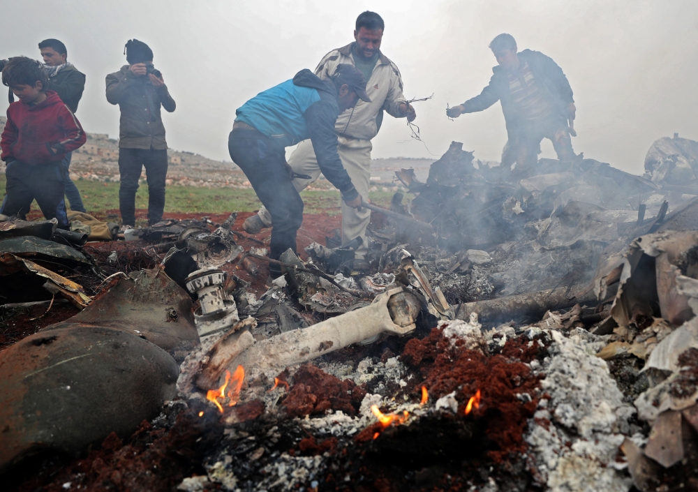 People search for scrapes of metal among the debris of a Syrian military helicopter that was shot down on February 14, 2020, in the western countryside of Aleppo province. (AFP / Omar HAJ KADOUR)