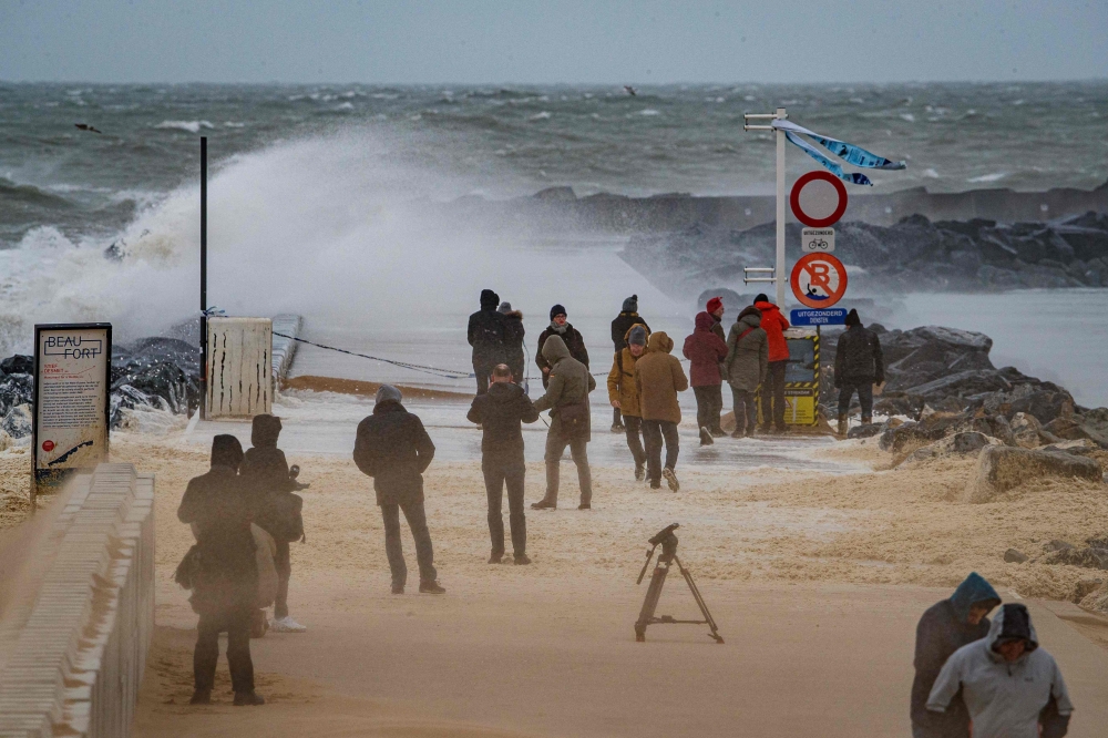 People stand on the beach as strong waves break against a jetty on the Belgian coast in Ostend on February 10, 2020, after storm Ciara swept over the country.  / AFP / BELGA / KURT DESPLENTER