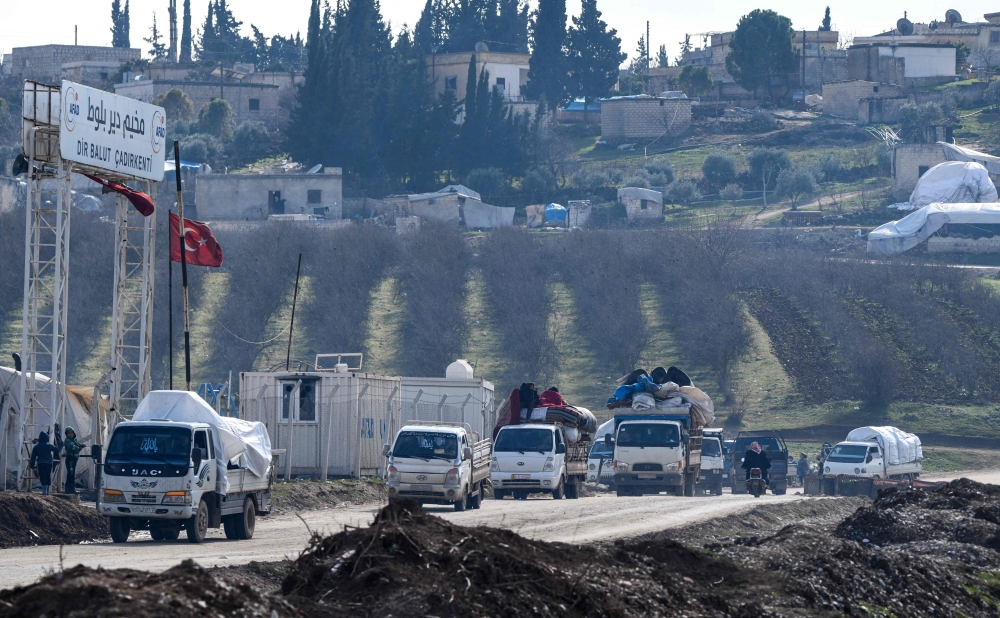 Vehicles carrying displaced Syrians pass by an internally-displaced persons (IDP) camp by Dayr Ballut near the Turkish border in the west of the northern province of Aleppo on February 15, 2020, as people flee advancing Syrian government forces in Idlib a