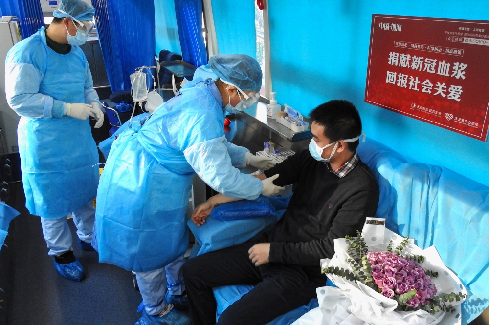 This photo taken on February 16, 2020 shows a man (R) who has recovered from the COVID-19 coronavirus infection donating plasma in Lianyungang in China's eastern Jiangsu province, aimed at curing infected patients in severe and critical conditions. China 