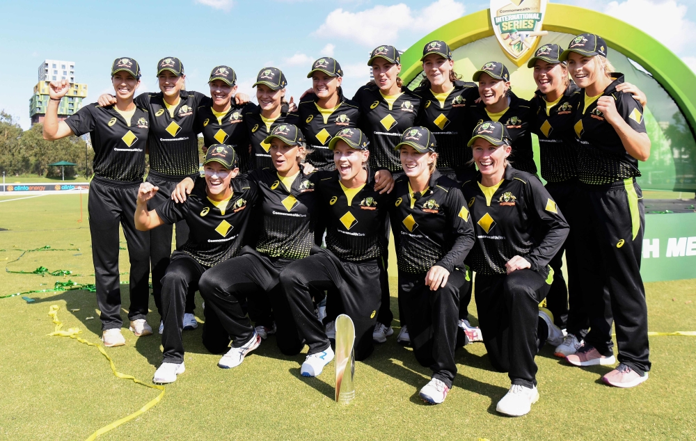 Australian players celebrate with the trophy after defeating India in the final of their women's T20 international tri-series cricket match in Melbourne on February 12, 2020. / AFP / William WEST