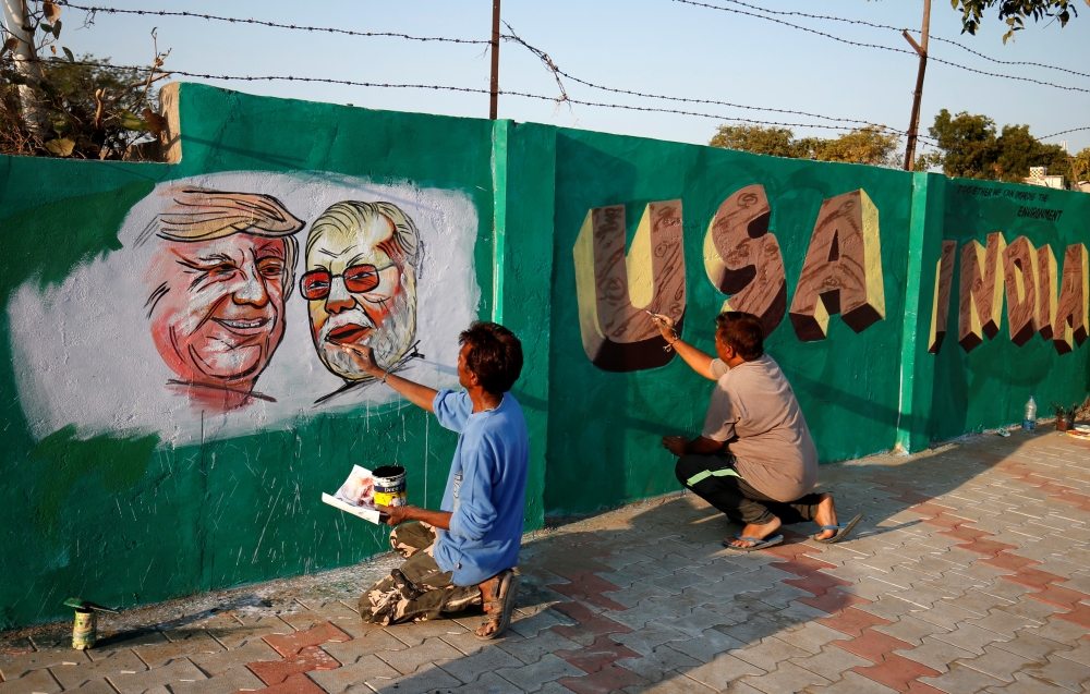 A man applies finishing touches to paintings of Donald Trump and Narendra Modi on a wall as part of a beautification along a route that they will be taking during Trump visit in Ahmedabad, India, February 17, 2020. Reuters/Amit Dave 
 