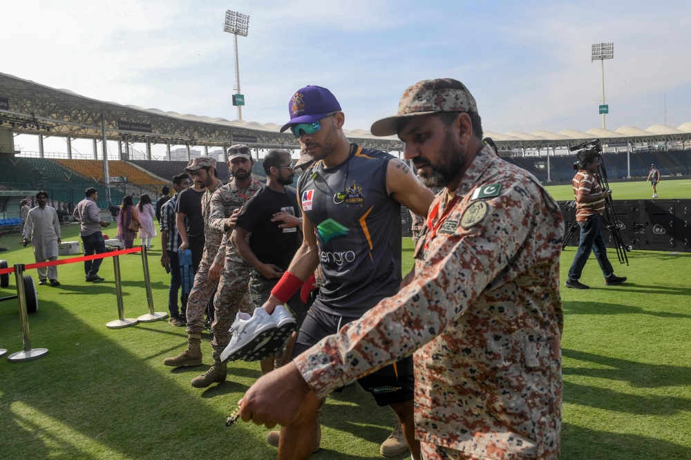 A ranger (R) escorts Quetta Gladiators' Tymal Mills (2R) of England as he leaves the ground after a practice session for the upcoming 2020 Pakistan Super League (PSL) at National Stadium in Karachi on February 18, 2020. The Pakistan Super League (PSL) 202