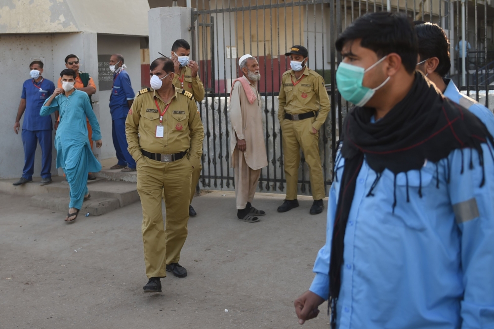  Security personnel (C) and hospital staff wearing facemasks stand outside an hospital entrance in Karachi on February 17, 2020, after a gas leak killed five people and sickened dozens of others in a coastal residential area in Pakistan's port city of Kar