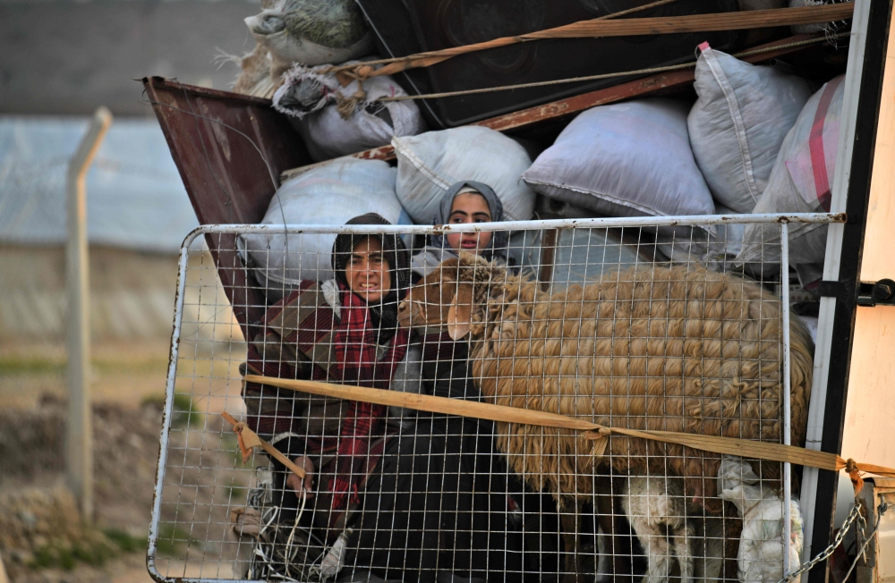Displaced Syrians ride in the back of a truck as they arrive to Deir al-Ballut camp in Afrin's countryside along the border with Turkey, on February 19, 2020. (AFP / Rami al SAYED)