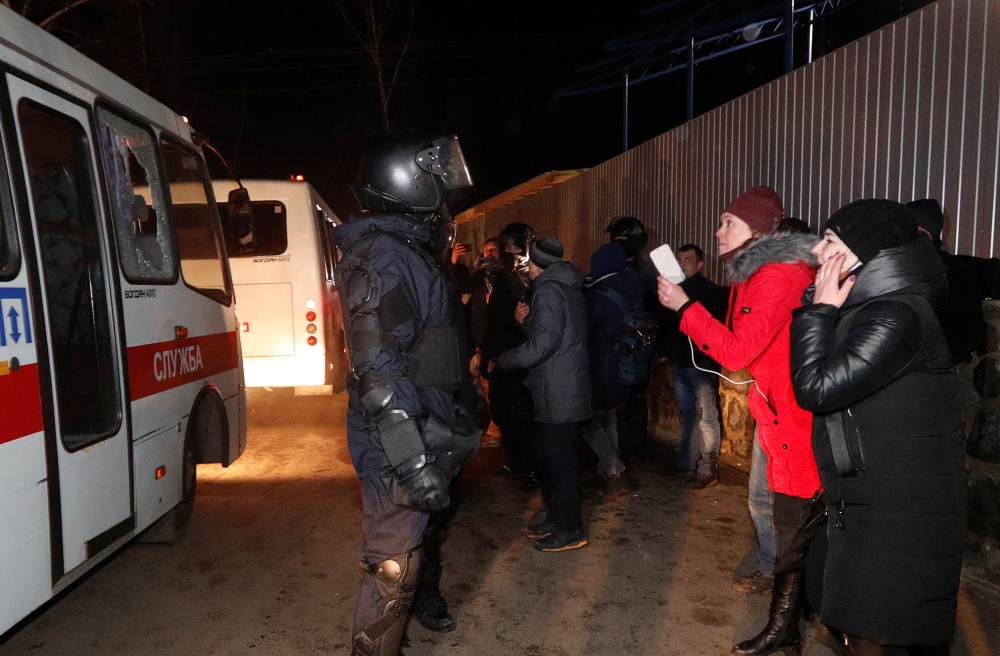 Buses transporting evacuees, who arrived from coronavirus-hit China's Hubei province, drive past demonstrators during a protest against their arrival near a sanatorium in the village of Novi Sanzhary in Poltava region, Ukraine February 20, 2020. REUTERS/V