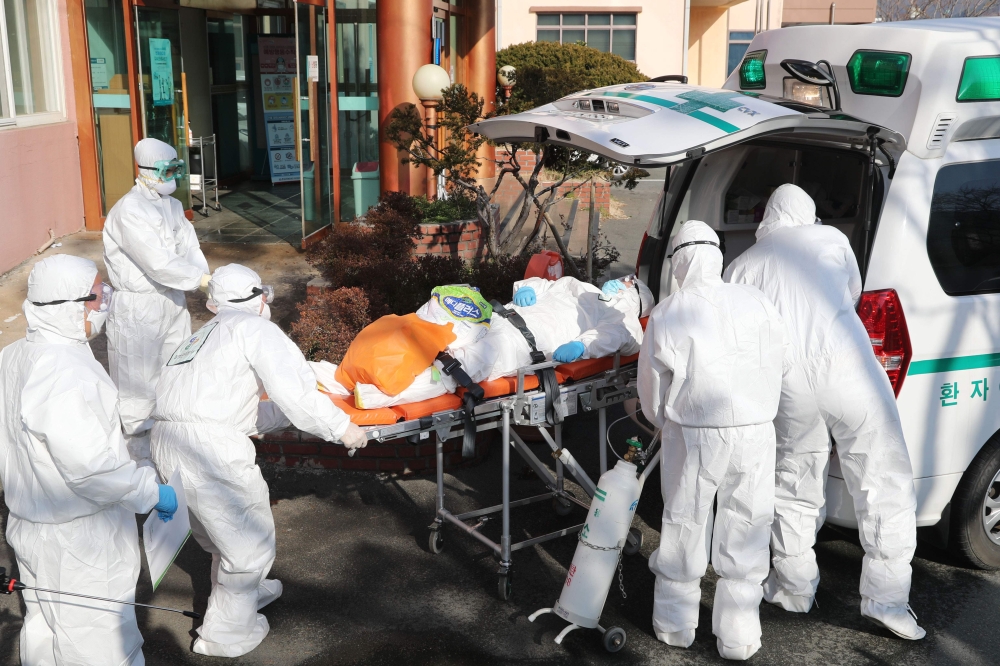 Medical workers wearing protective gear transfer a suspected coronavirus patient (C) to another hospital from Daenam Hospital where a total of 16 infections have now been identified with the COVID-19 coronavirus, in Cheongdo county near the southeastern c