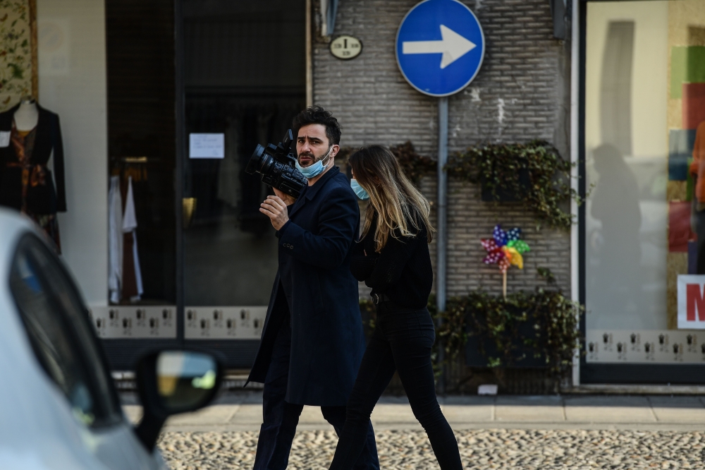 Reporters wearing protective surgical mask walk across Codogno, southeast of Milan, on February 22, 2020.   AFP / Miguel MEDINA