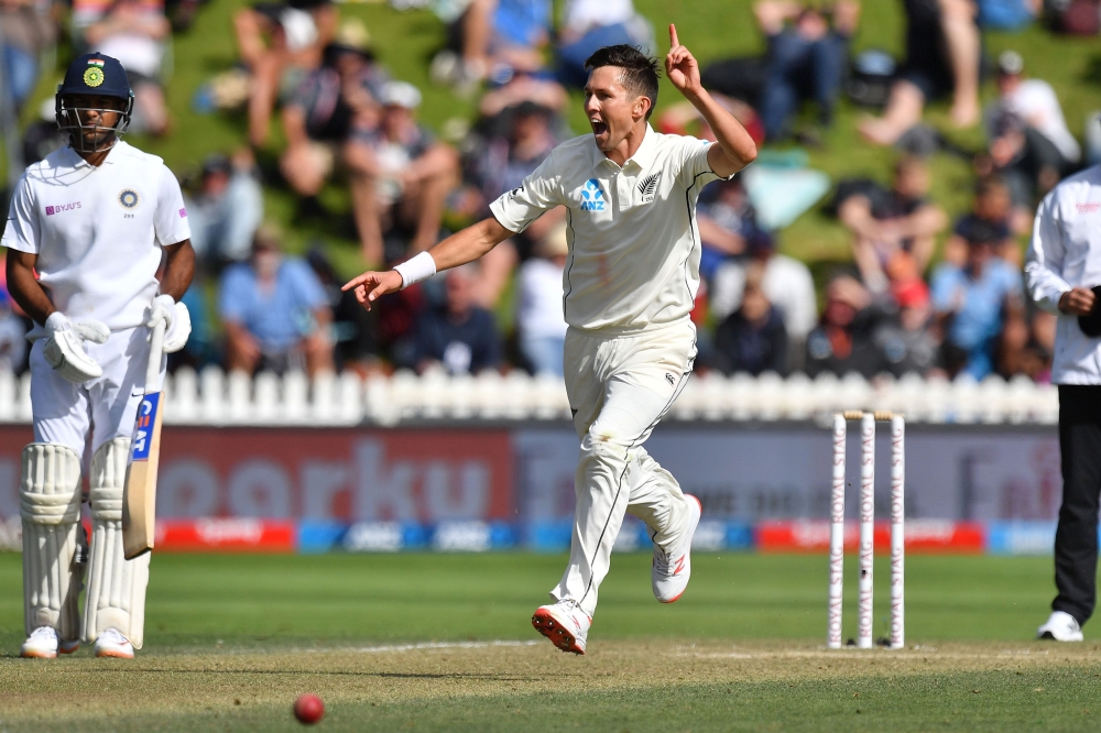 New Zealand's Trent Boult (R) celebrates bowling India's Cheteshwar Pujara and watched by Mayank Agarwal during day three of the first Test cricket match between New Zealand and India at the Basin Reserve in Wellington on February 23, 2020. / AFP / Marty 