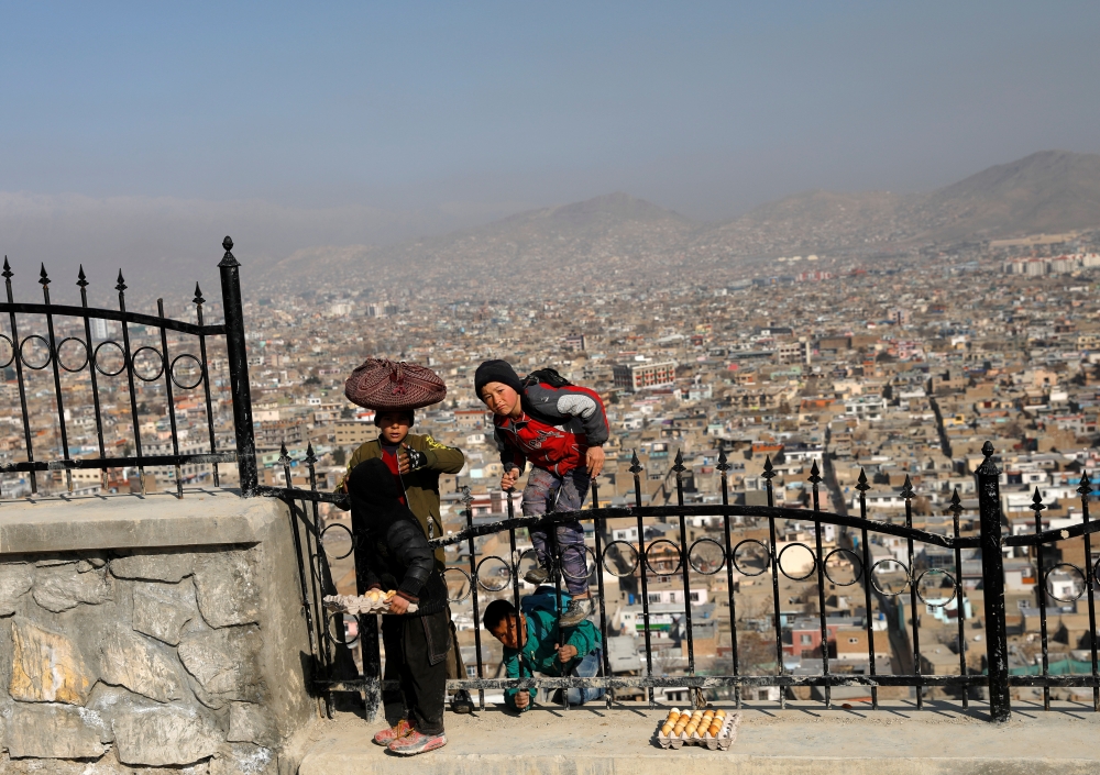 Afghan boys who sell boiled eggs climb to a hilltop overlooking Kabul, Afghanistan February 23, 2020. REUTERS/Mohammad Ismail
