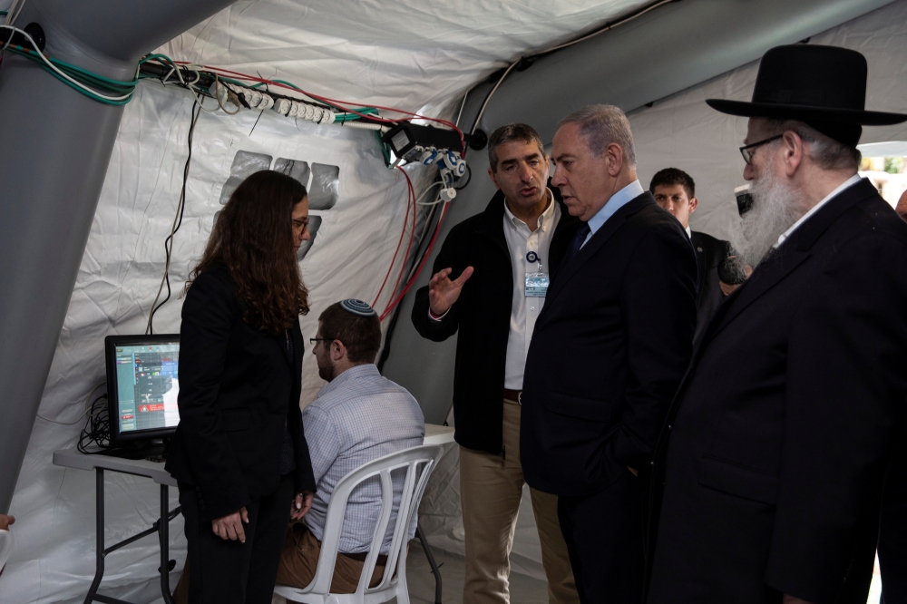 Israeli Prime Minister Benjamin Netanyahu arrives to a tent during his visit to the Chaim Sheba Medical Center at Tel Hashomer in Ramat Gan, Israel, for discussion on the coronavirus, February 19, 2020. Heidi Levine/Poolvia Reuters