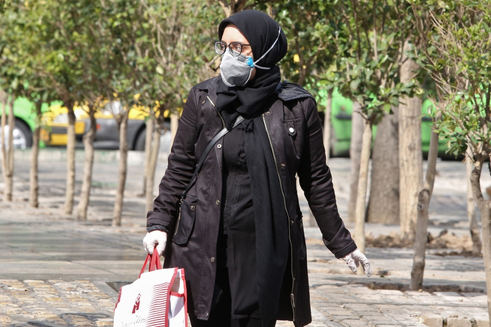 A woman wears a protective mask while walking along the side of a street in the Iranian capital Tehran on February 24, 2020. AFP / ATTA KENARE
