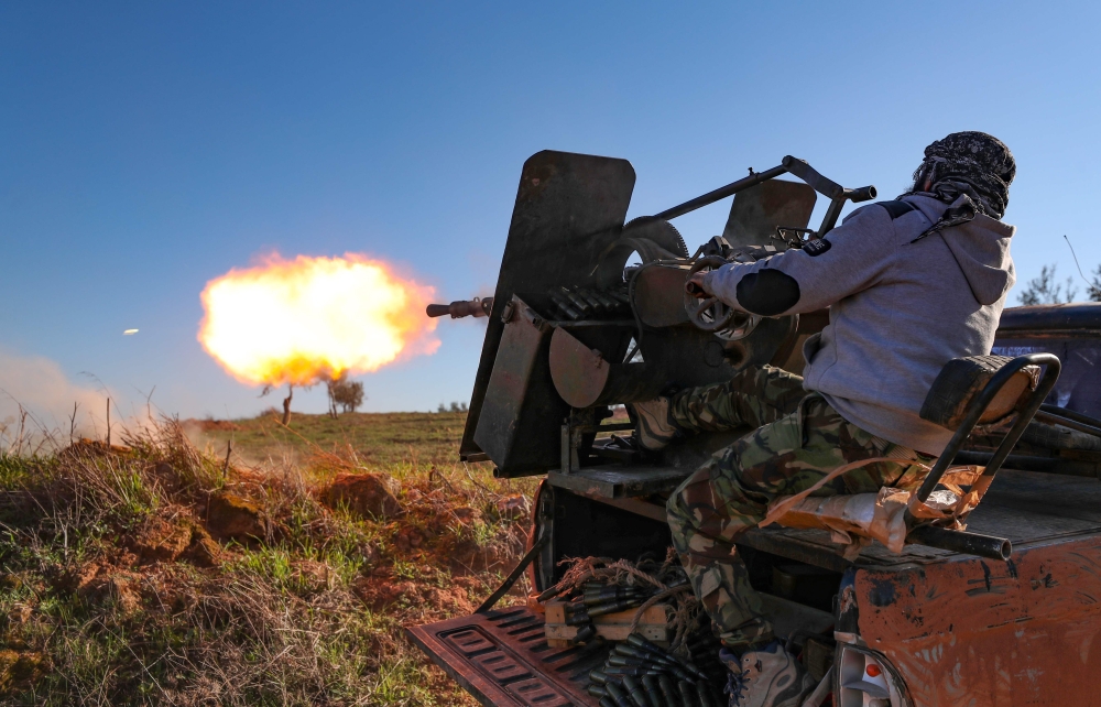 A Turkey-backed Syrian fighter fires a truck-mounted gun toward the town of Saraqeb from the outskits of the villages of Afis and Salihiyah situated near the regime-controlled town, in the eastern part of the Idlib province in northwestern Syria, on Febru