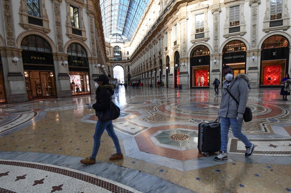 Tourists wearing protective face masks walk in Galleria Vittorio Emanuele II in the centre of Milan, on February 28, 2020, after COVID-19, the novel coronavirus, spread to Italy. AFP / Miguel Medina 
