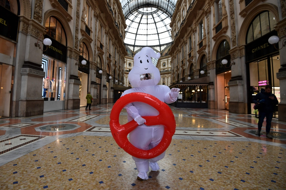 A man disguised in a ghost outfit walks around a near-deserted Galleria Vittorio Emanuele II luxury mall on February 29, 2020, in central Milan, northern Italy.  AFP / Miguel MEDINA