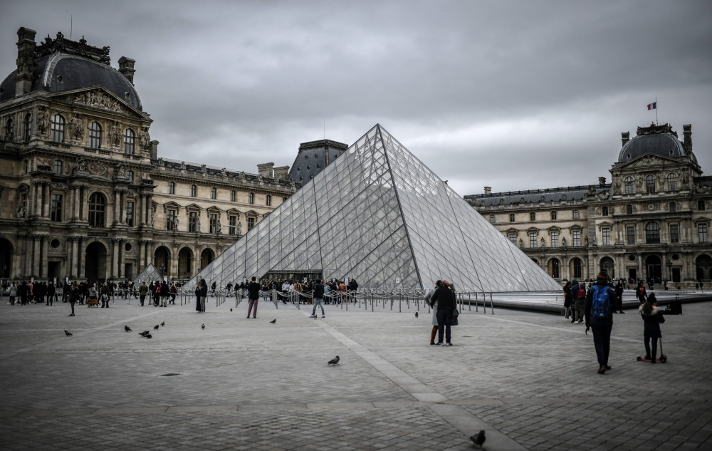 In this file photo taken on February 28, 2020 people visit the Louvre Pyramide in Paris.  AFP / Stephane De Sakutin 
 