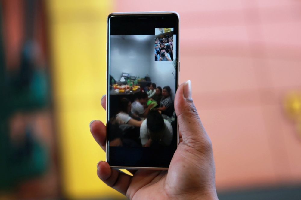 A police officer holds a phone where the gunman and hostage-taker of at least a dozen is on a video call inside a mall in San Juan City, Metro Manila, Philippines, March 2, 2020. REUTERS/Eloisa Lopez