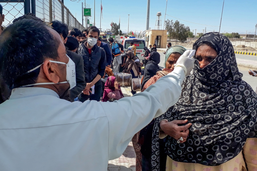 A health personnel checks the body temperature of a pilgrim returning from Iran via the Pakistan-Iran border town of Taftan on February 29, 2020. Health officials in Pakistan are screening hundreds of people who had recently arrived from Iran, a major new