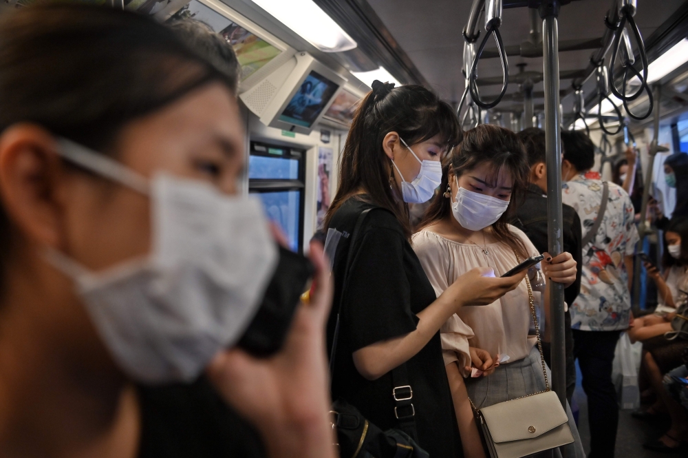 People wearing face masks ride the BTS Skytrain station in Bangkok on March 7, 2020.  AFP / Lillian SUWANRUMPHA