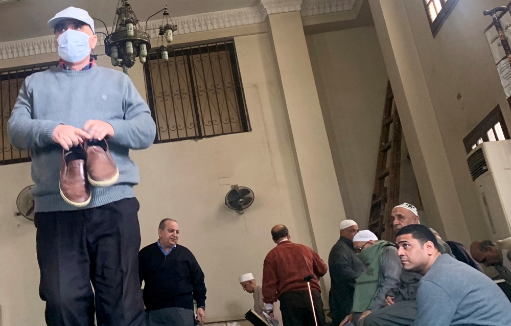 People look at a man wearing a protective mask as a means of prevention against the coronavirus disease (COVID-19) at the Al Rahman mosque, after Friday prayers, in the southern suburb of Maadi, on the outskirts of Cairo, Egypt March 6, 2020. REUTERS/Amr 