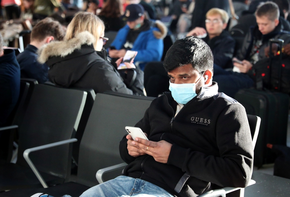 A man wears a surgical mask as he sits in Terminal 5 at Heathrow Airport in London, Britain March 6, 2020. REUTERS/Hannah McKay