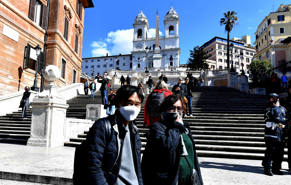 Tourists wearing protective masks visit Piazza di Spagna in Rome on March 8, 2020. AFP / Tiziana FABI
